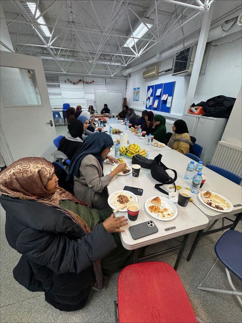 Mothers sharing breakfast around a long table at a coffee morning